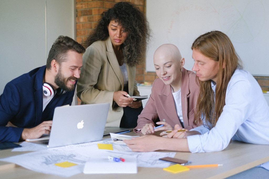 Group of employees around a laptop discussing diversity initiatives in the workplace