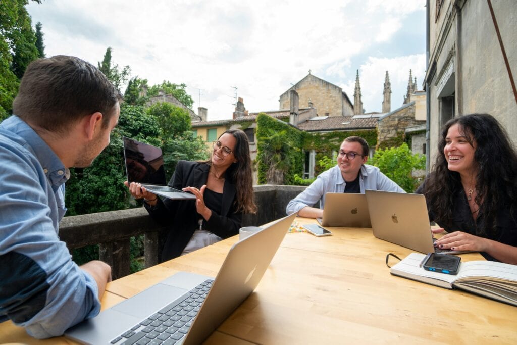 Employees at a table with laptops discussing skills-based hiring.