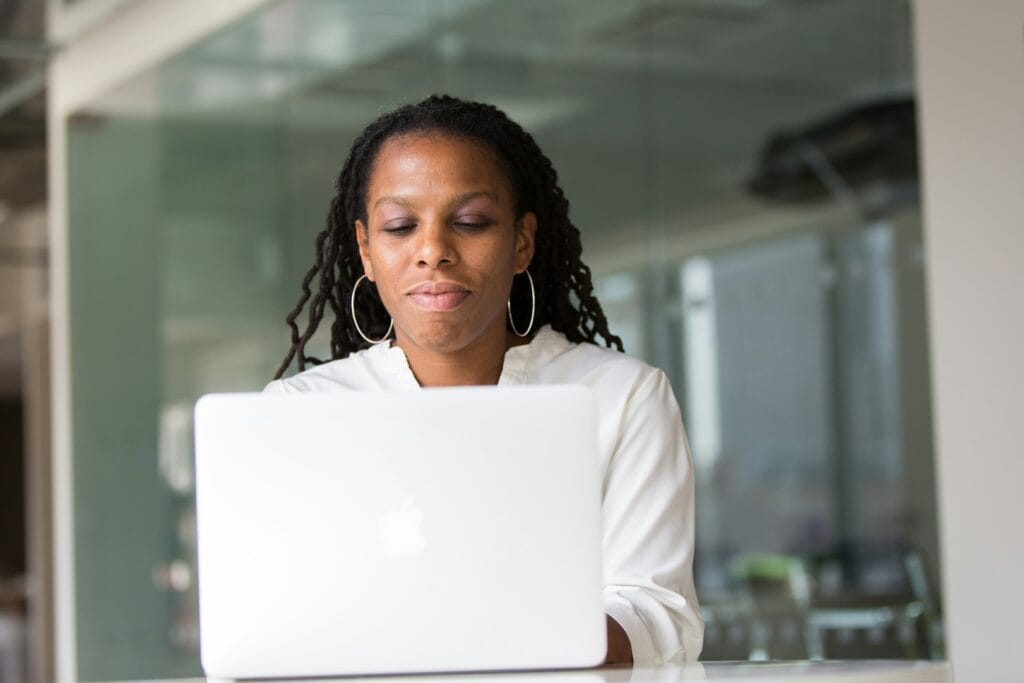 A woman sitting at a laptop using an AI coaching app.