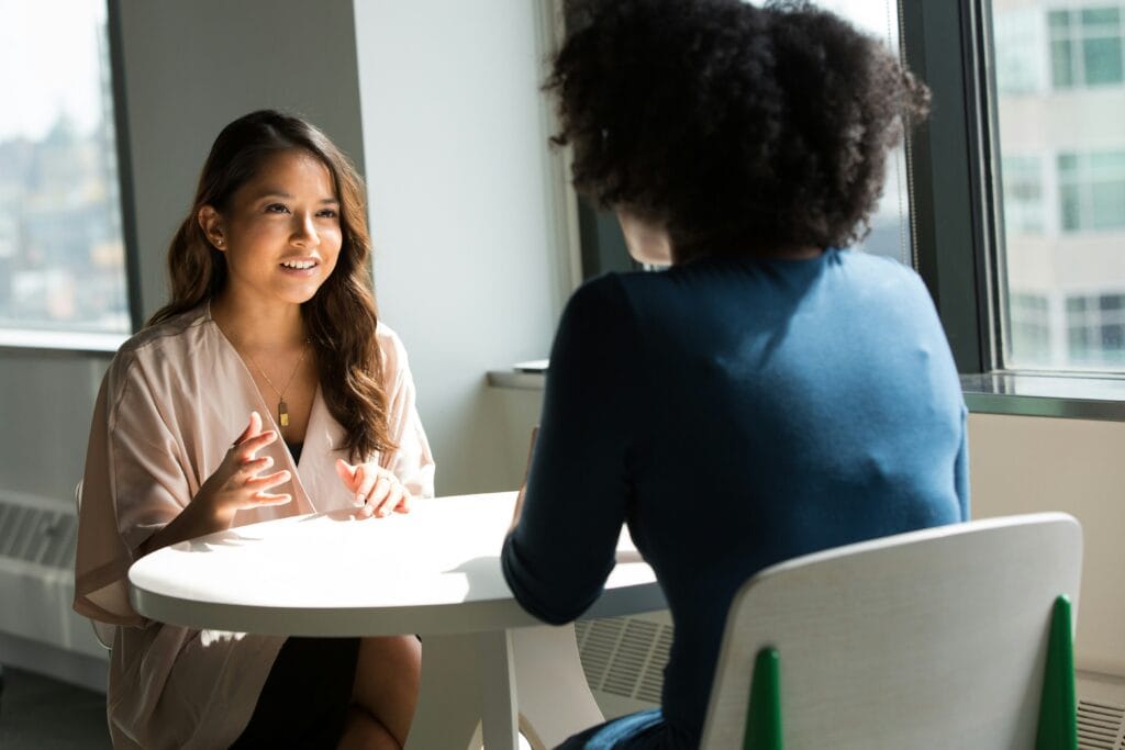 Two women sitting at a table discussing HR Leadership strategies.