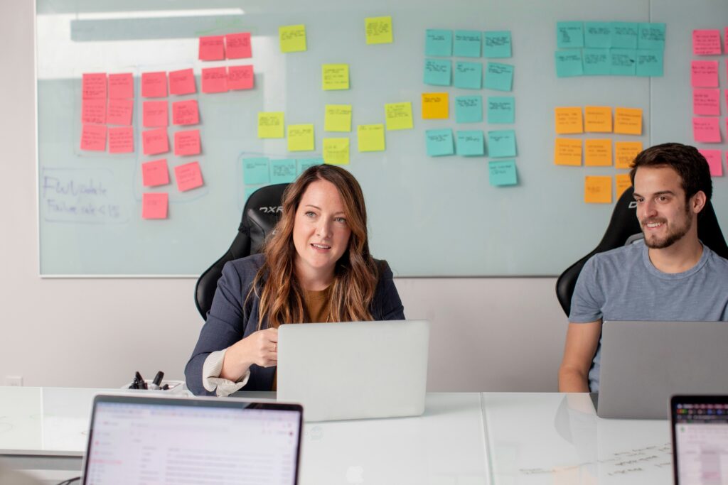 Professionals at a conference table using laptops discussing strategic HR.