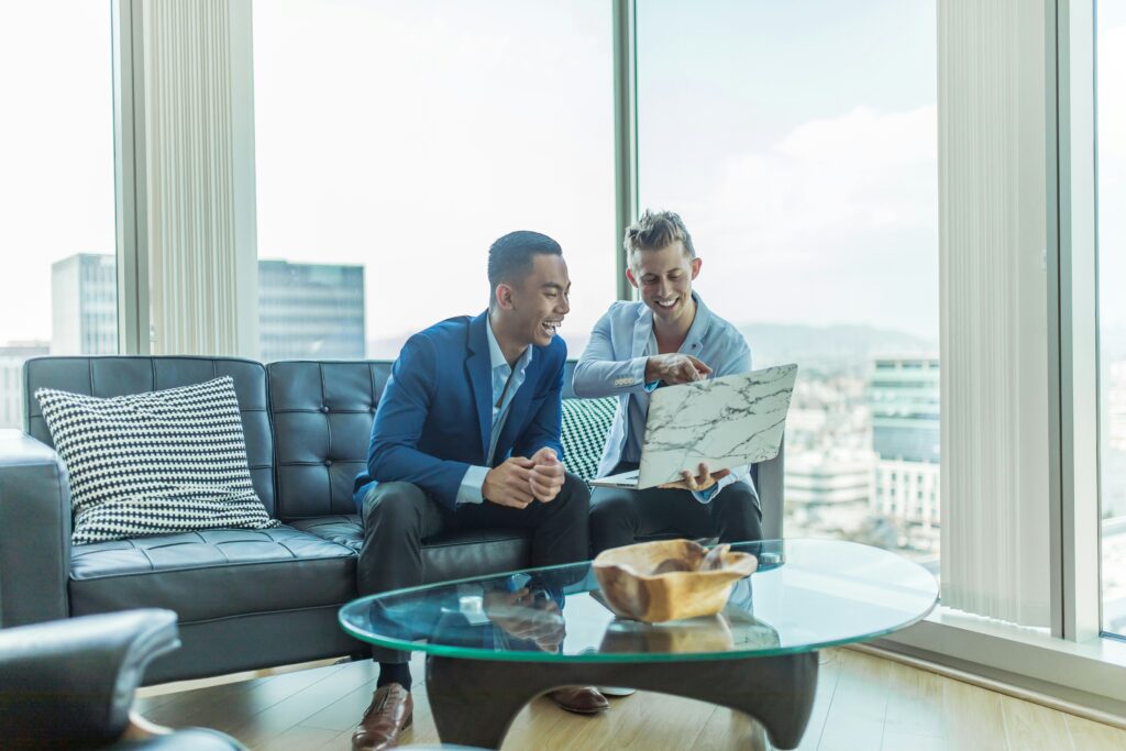 Two managers sitting on a couch looking at a laptop where they are recruiting freelancers.