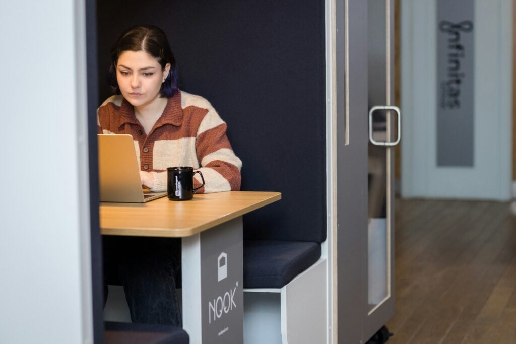 Woman sitting at a laptop in booth learning about her HR tech stack.