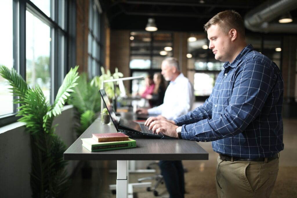 Man at a standing desk working on his laptop on generative AI in HR.
