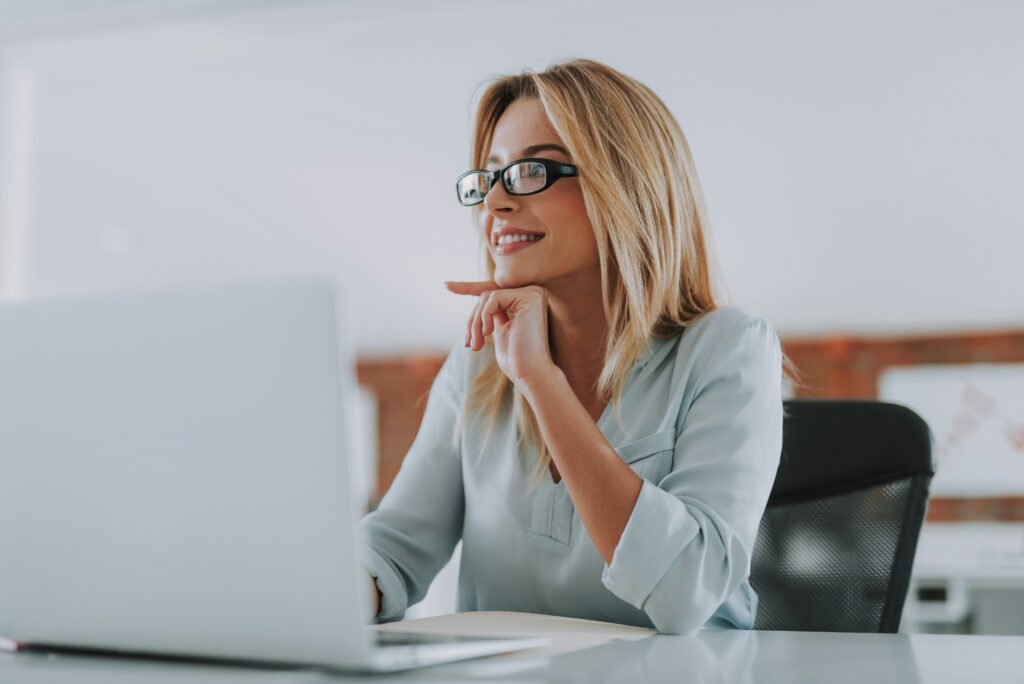 Woman sitting at laptop smiling using candidate screening tools.