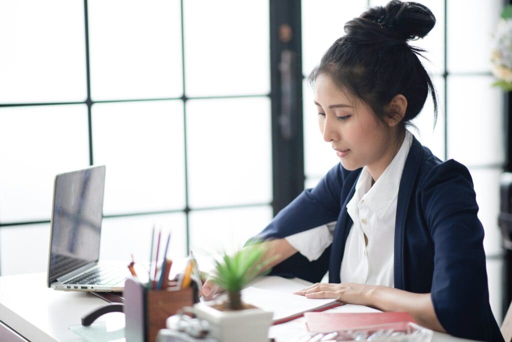 Woman sitting at desk using AI resume screening to review candidates.