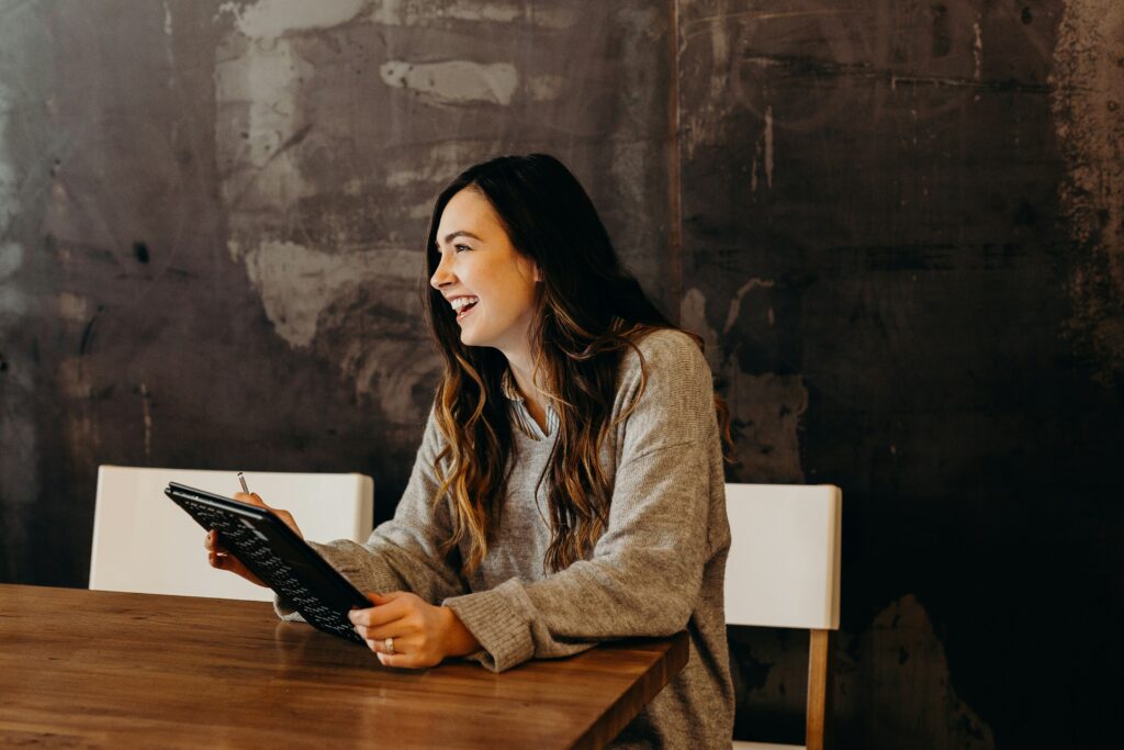 Woman smiling sitting with an ipad learning about transparent AI in hiring.