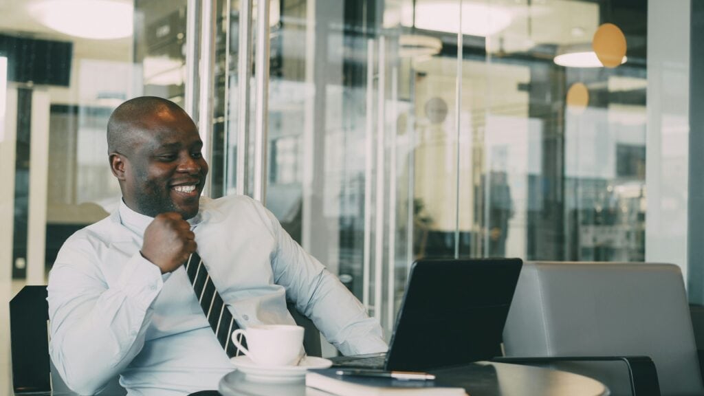 Man sitting at his laptop smiling at the screen.