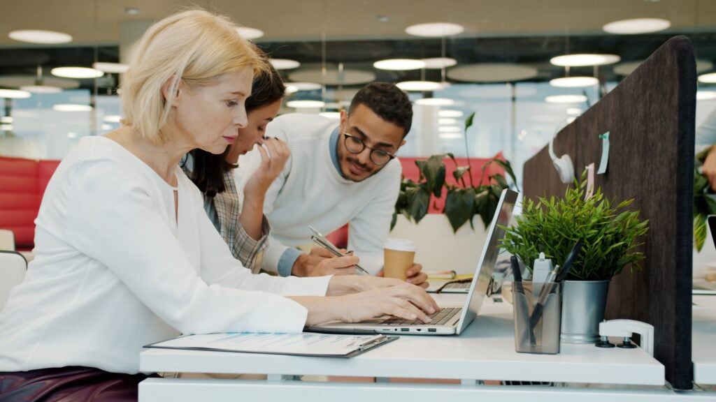 Woman sitting at laptop typing using data to calculate hiring ROI